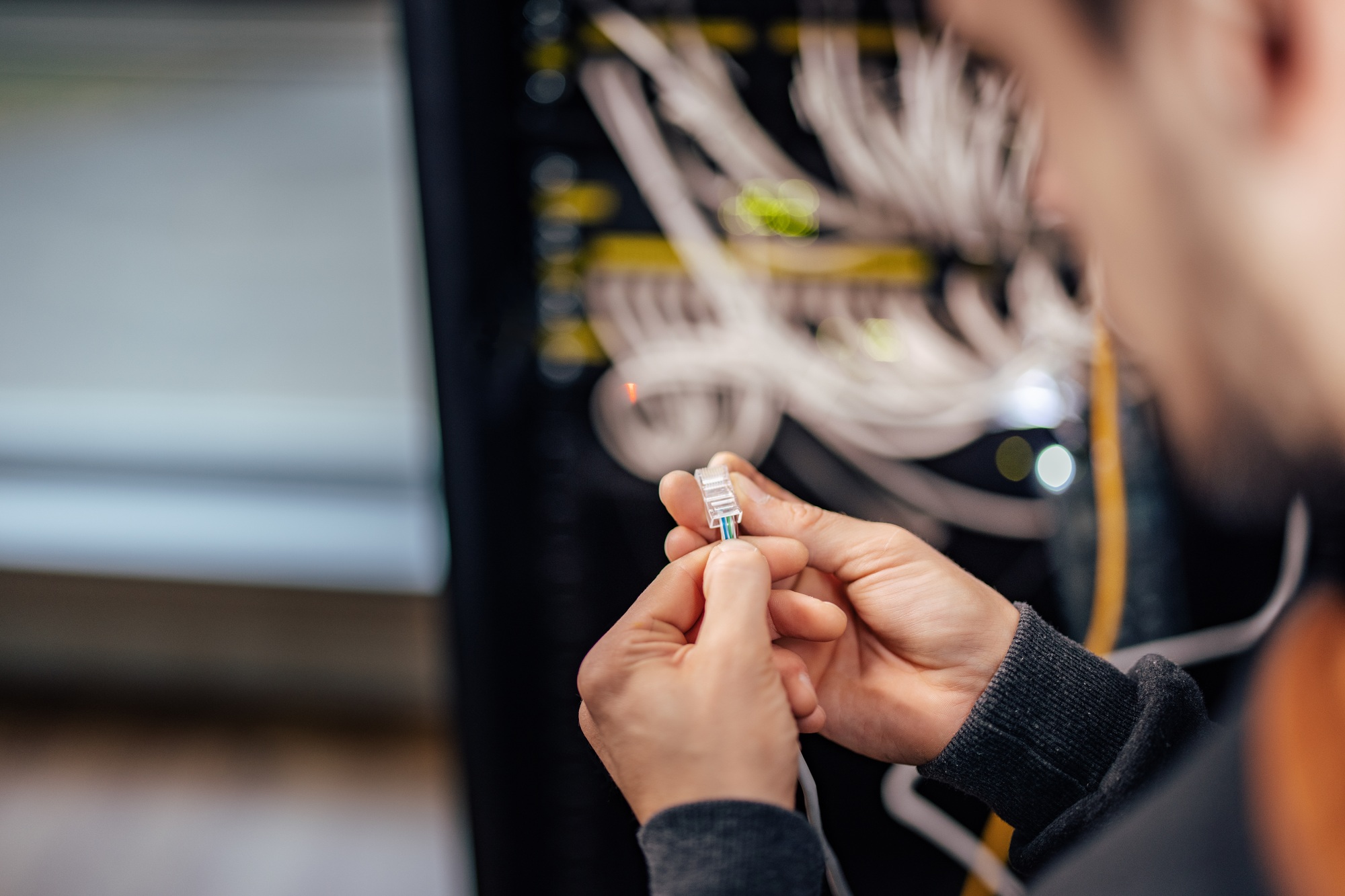 Technician inspecting ethernet jack, at data center.